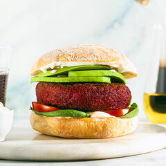 vegan burger without meat with avocado, tomatoes and spinach on the table and red wine in a glass