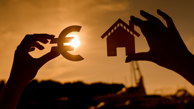 Euro symbol and house in women's hands contoured at sunset