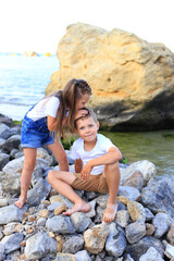 Two children are on the rocks by the sea