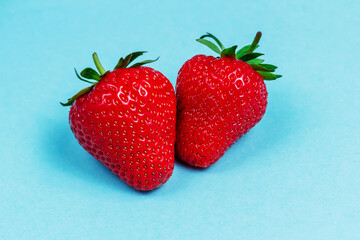 Two berries of ripe delicious strawberries lie on a blue background. Background with strawberries. Summer berries. 