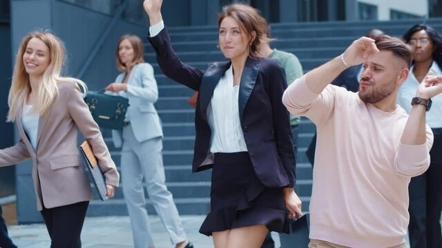 Excited multi-ethnic co-workers dancing on the street celebrating triumph in business career success cooperation. Staff. Holiday concept.