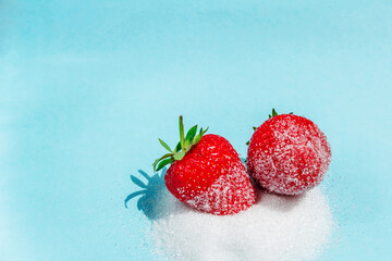 Two berries of ripe delicious strawberries lie on sugar on a blue background. Background with...