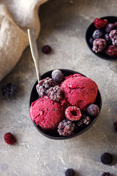 Delicious summer berries yogurt ice cream with berries on grey background, frozen berries, vegetarian ice cream