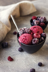 Delicious homemade summer berries yogurt ice cream with frozen berries on grey background