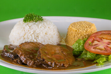 roast beef with rice and salad on the green background is a traditional dish of Brazilian cuisine