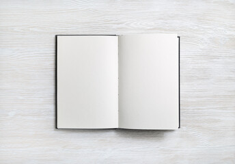 Open blank book on light wood table background. Space for text. Flat lay.
