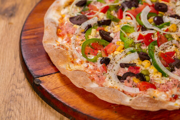Portuguese Pizza, onion, peppers, pepperoni, egg, olive on wooden background