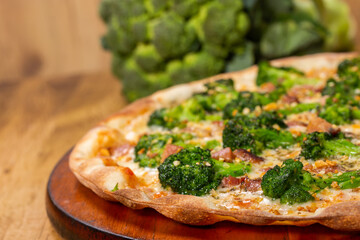 closeup of a broccoli pizza in front of a wooden background. Space for text