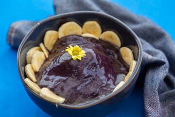 Delicious açai bowl with banana on blue background