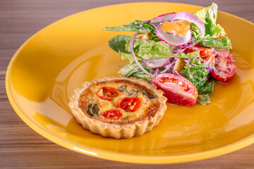 delicious quiche with salad, served in yellow dishes