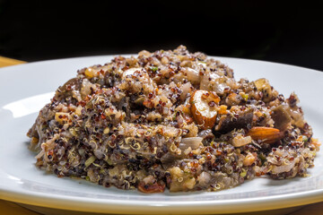 quinoa salad with nuts served in white dishes on black background