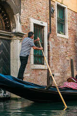 Fototapeta na wymiar Gondoliere sailing on the canals of Venice