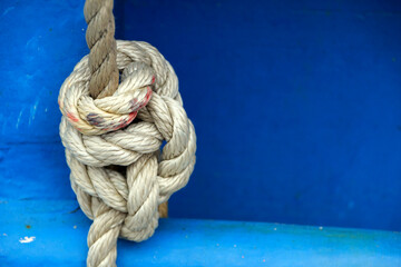 Knot on a rope, blue background with copy space. Nautical concept