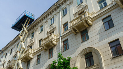 Scissors mechanism elevator against the background of a renovated apartment building. Repairs concept.