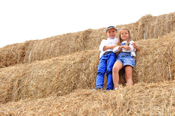 Naklejka na ściany i meble Two children are high under the sky on a haystack in the hay season.