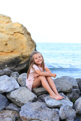 A child on the stones near the sea in summer.