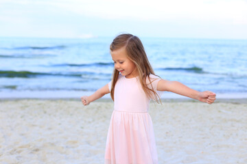 Fototapeta na wymiar Cute girl stands on the seashore in summer
