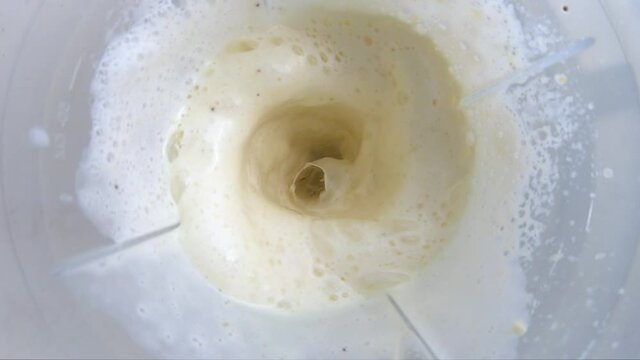 Banana smoothie with milk, beat in a blender. Top view and slow motion. GOPRO HERO7 1080 FullHD 240fps