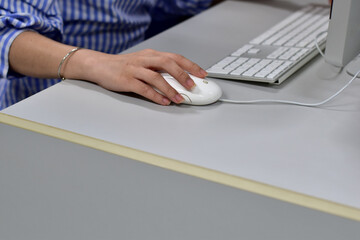 Closeup of Young Woman using a computer, Hand held mouse and keyboard, On a clean desk.