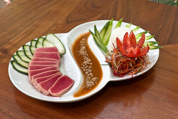 plato de sashimi de atún rojo crudo en rebanadas con vegetales y salsa a la mostaza, plato blanco sobre mesa de madera, vista de arriba