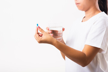 Closeup young Asian woman hold pill drugs in hand ready take medicines with a glass of water, studio shot isolated on white background, Healthcare and medical pharmacy concept