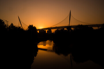 Fototapeta na wymiar People crossing the bridge at sunset and reflection