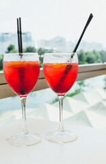 Closeup glasses of cocktail decorated with oranges on the table. Colorful pink soft drinks with ice and straws in a cafe.	