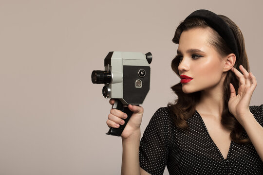 Girl in pin-up style holds a retro camera in her hand.