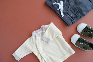 Tiny shirt, pants and little sneakers on brown background. Infant clothes concept.