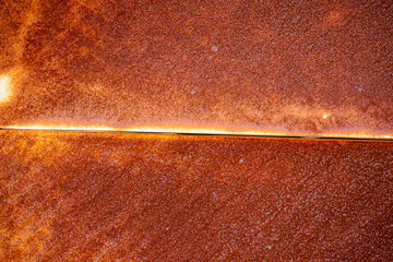 rusted sheet of metal, orange corrosion and horizontal strip, joint