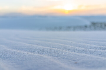 White sands dunes national monument park and foreground closeup of pattern in New Mexico with sun over horizon at sunset