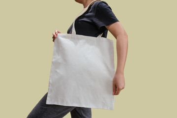Woman holding reusable white cotton linen eco organic fabric tote bag isolated blank background for...