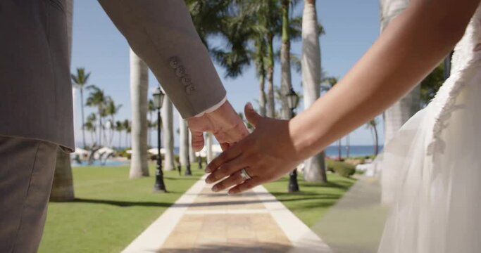 Bride and groom holding hands together in a beautiful tropical resort. 