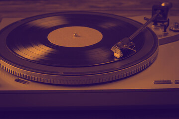 Tinted image of a vinyl record player on a wooden background.