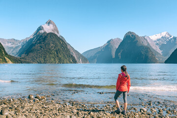 New Zealand - tourist couple hiking looking at Milford Sound enjoying iconic view and famous tourist destination in Fiordland National Park, South Island, New Zealand.