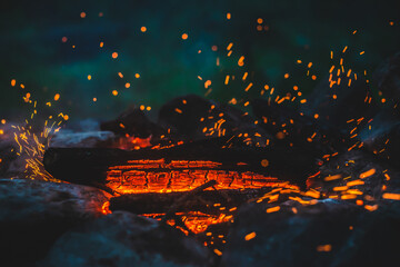 Vivid smoldered firewoods burned in fire close-up. Atmospheric background with orange flame of...