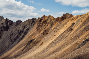 Atmospheric landscape with rocky mountain wall with pointy top in sunny gold light. Beautiful golden rock pinnacle in sunlight. Awesome mountain scenery with pointed rockies. Sharp stony mountains.