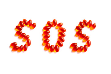 The letters SOS written in orange and red vitamins and pills on a white background. Isolate Close-up.