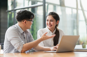 Obraz premium Asian business people man and woman conference talking and working with laptop together. Young couple work at home.