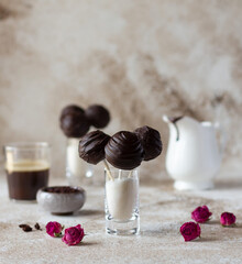 Cake pops covered with dark chocolate in glasses filled with sugar powder, delicious dessert, mix of cake crumbs and cream
