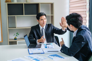 Happy young asian businessman successful  giving a high fives showing cooperation and success at work.