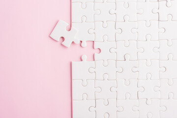 Top view flat lay of paper plain white jigsaw puzzle game texture last pieces for solve and place, studio shot on a pink background, quiz calculation concept