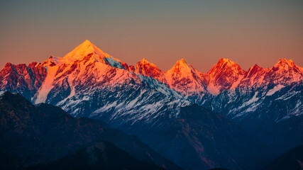 Fototapeta na wymiar Panoramic view during sunset over snow cladded Panchchuli peaks falls in great Himalayan mountain range from small hamlet Munsiyari, Kumaon region, Uttarakhand, India.