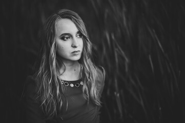 Portrait of a beautiful girl stand in autumn in dress against the background of the field on the nature. upper half. look to the side. Close up. headshot. Black and white photo.