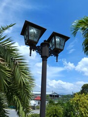 Street lamp post, with green trees and blue skies as the background