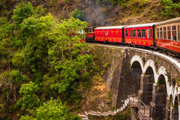 View from moving train on arch bridge over mountain slopes, beautiful view, one side mountain, one side valley. Toy train from Shimla to Kalka in Himachal Pradesh, India - obrazy, fototapety, plakaty