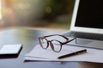 Close up glasses and paper work on desk work in home.