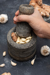 Ginger garlic paste with mortar and pestles homemade paste spicy herb ingredient of Thai Asian food. Fresh mashed Adrak and Lahsun on dark black background