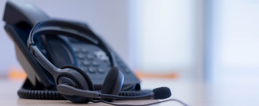 close up on headset with telephone devices at office desk for customer service support concept