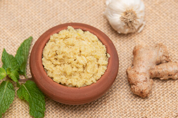 Ginger garlic paste with mortar and pestles homemade paste spicy herb ingredient of Thai Asian food. Fresh mashed Adrak and Lahsun on dark black background